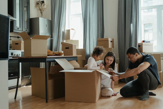 family of three surrounded by moving boxes